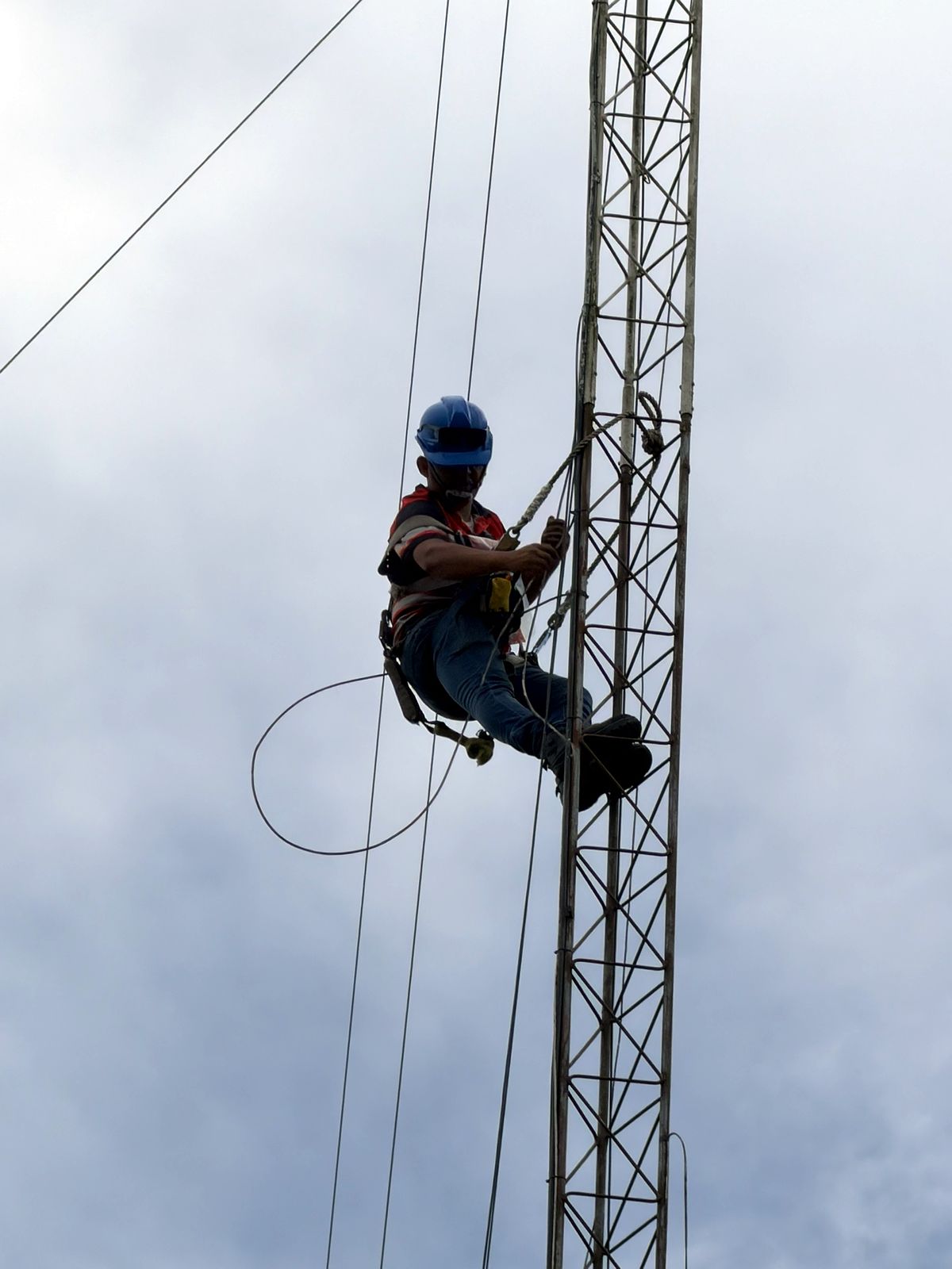 Técnico con casco y arnés trabajando en altura sobre torre de telecomunicaciones en Guatemala